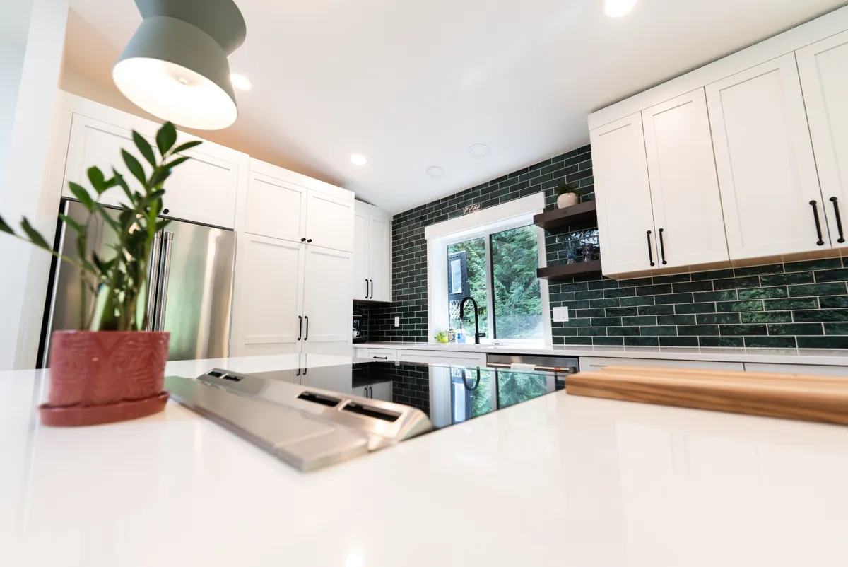 Kitchen with white cabinets and green glass tile backsplash